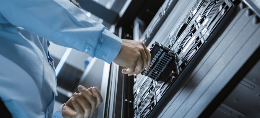 Man inserting a hard drive into server rack